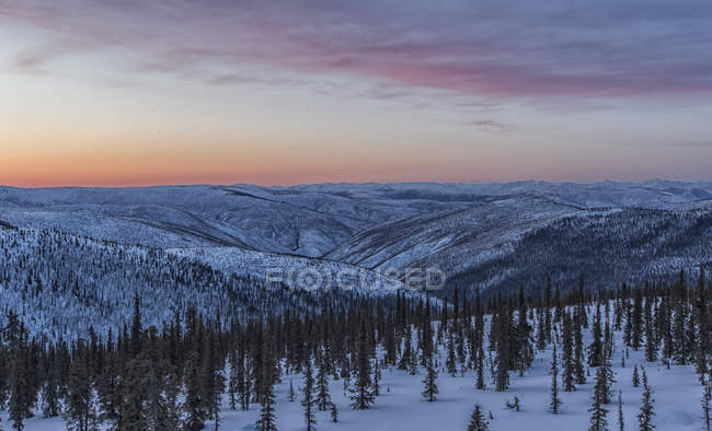 Nuvens de pôr do sol sobre a pradaria coberta de neve e florestas de Dawson City, Yukon . — Fotografia de Stock