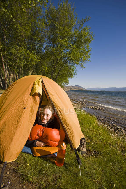 Молодая женщина лежит в палатке, озеро Скаха, Пентиктон, Британская Колумбия, Канада — стоковое фото
