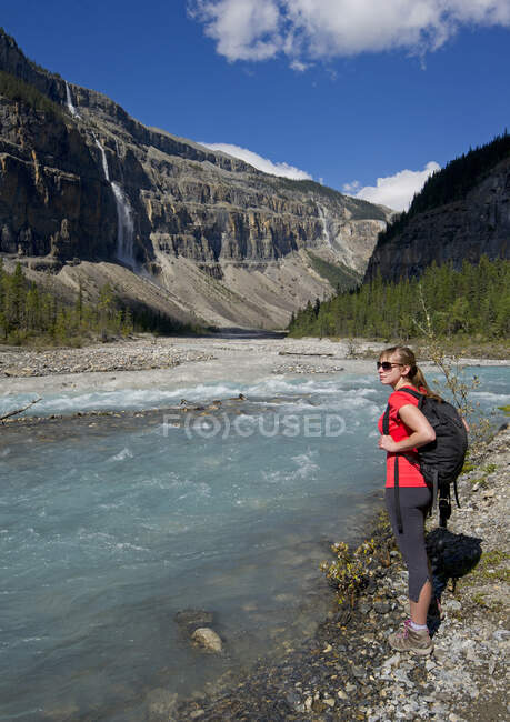 Una giovane donna attraente ammira la 'Valley of a Thousand Falls' mentre si trova sul sentiero Robson di Mount Robson, appena a nord di Valemount, nella regione Thompson Okanagan, Columbia Britannica, Canada — Foto stock