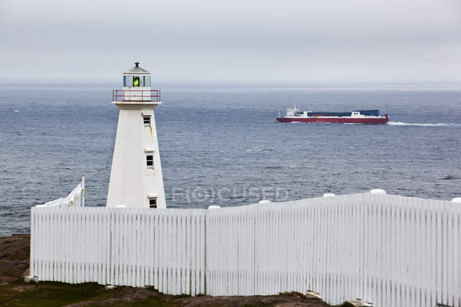 Lighthouse and passing cargo ship at Cape Spear, Newfoundland — Stock Photo