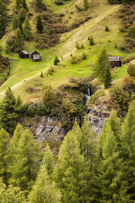 Kleine Holzhütten an grünen Hängen der Dolomitenberge in Norditalien. — Stockfoto
