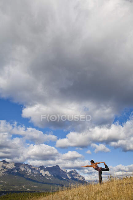 Mujer en forma practicando yoga en la colina en el campo de Canmore, Canadá - foto de stock