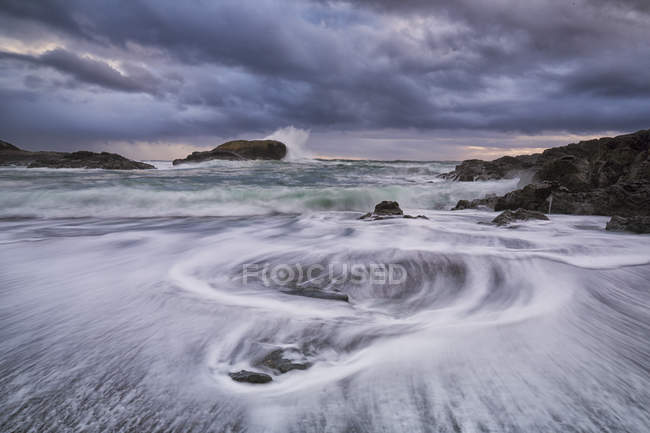 Agua que fluye alrededor de rocas de South Beach en el Parque Nacional Pacific Rim, Columbia Británica, Canadá . - foto de stock
