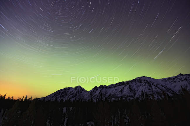 Luces boreales con senderos estelares sobre montañas en las afueras de Whitehorse, Yukón, Canadá . - foto de stock