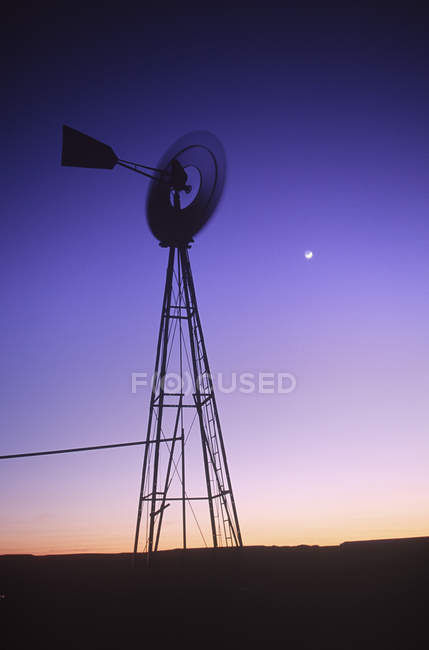 Wind powered water pump and moon at twilight in New Mexico, USA — Stock Photo