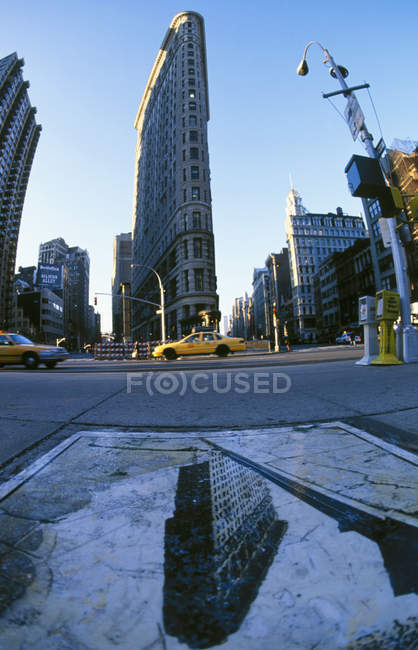 Edifício Flatiron refletindo em água e táxis amarelos da calçada de Nova York, EUA — Fotografia de Stock