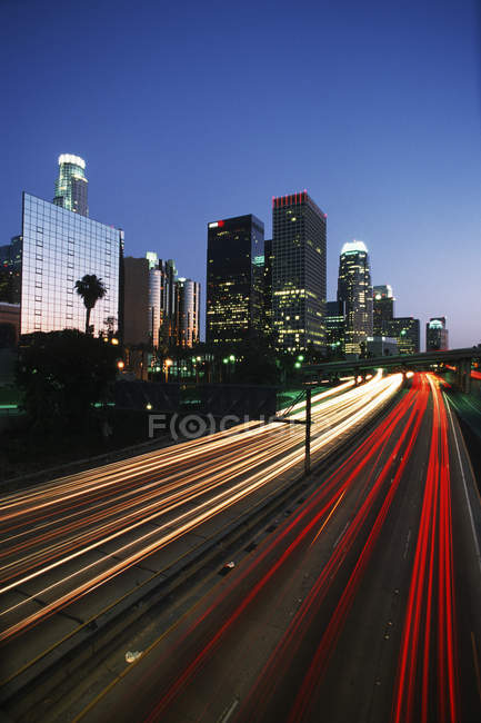 Ciudad skyline en el crepúsculo con autopista, Los Ángeles, California, EE.UU. - foto de stock
