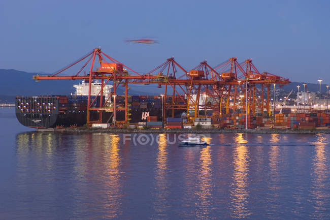 Puerto de Vancouver, grúas y carguero al atardecer, Columbia Británica, Canadá . - foto de stock