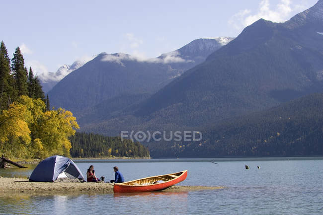 Homem e mulher descansando por barraca no Bowron Lake Provincial Park, British Columbia, Canadá . — Fotografia de Stock
