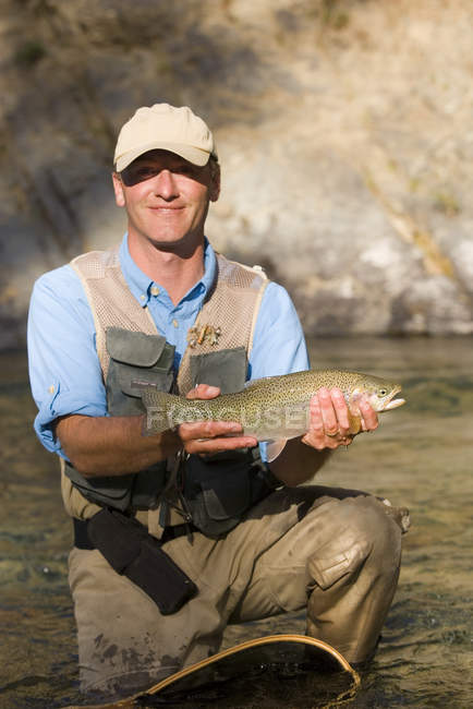 Mann trägt halsbrecherische Forellen auf einem Nebenfluss des Elchflusses in der Nähe von Fernie, British Columbia, Kanada. — Stockfoto
