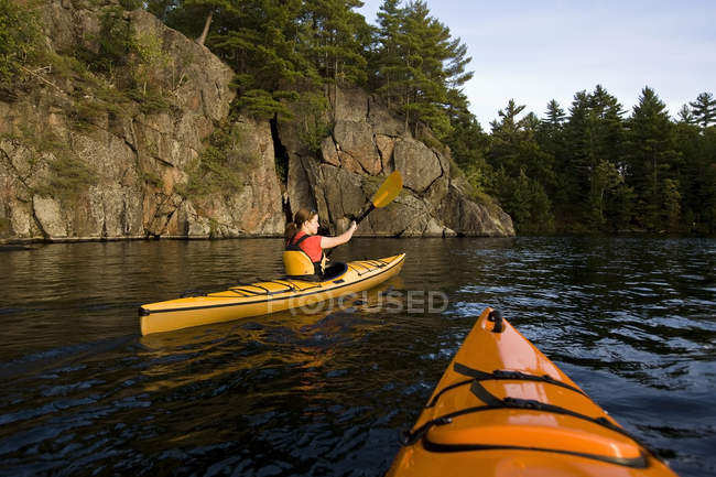 Giovane donna in kayak da mare attraverso Gull Narrows vicino Gravenhurst, Muskoka, Ontario, Canada
. — Foto stock