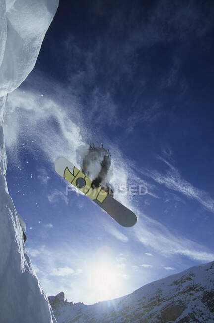 Vista ad angolo basso di uno snowboarder che prende un po 'd'aria nel backcountry, Golden, British Columbia, Canada — Foto stock