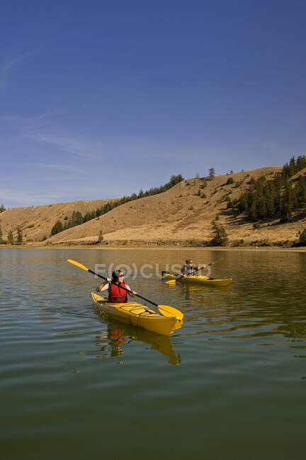 Hombre y mujer remando en el agua del lago Trapp, Kamloops, Columbia Británica, Canadá - foto de stock