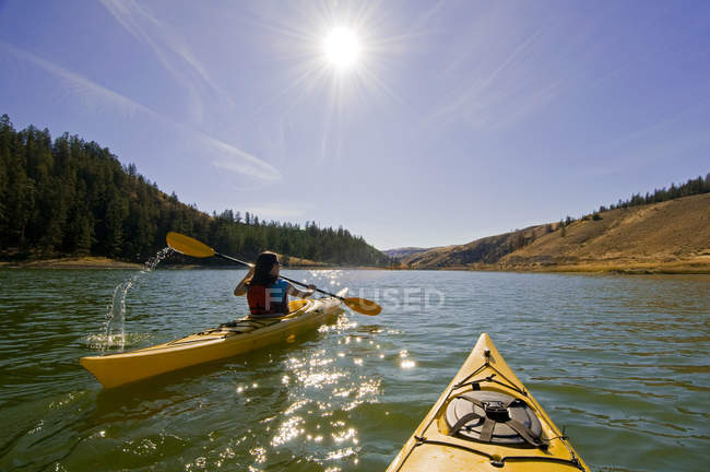 Vue arrière du kayak féminin en plein soleil au lac Trapp, près de Kamloops, Colombie-Britannique, Canada — Photo de stock
