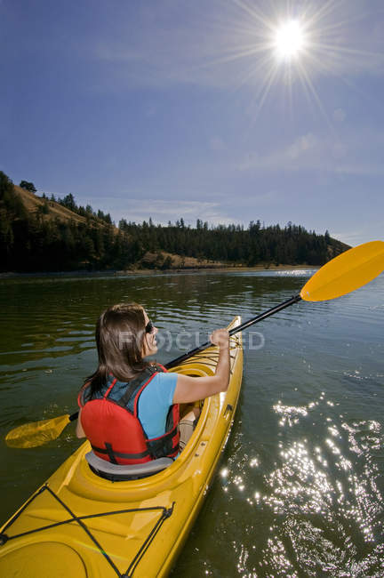 Jeune femme faisant du kayak au soleil sur le lac Trapp près de Kamloops, Colombie-Britannique, Canada — Photo de stock