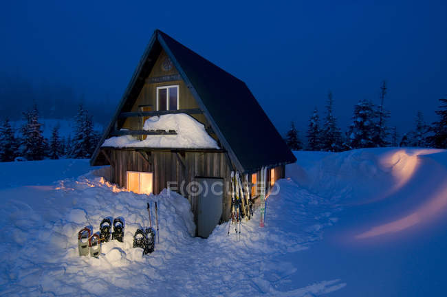 Pintoresca cabaña en hermosos paisajes al atardecer con raquetas de nieve en la nieve cerca del río Powell, Columbia Británica, Canadá - foto de stock