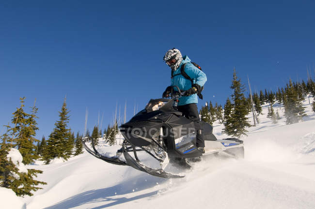 Singolo cavaliere facendo strada verso il basso pendio mentre motoslitta a Monashees, Thompson Okanagan, British Columbia, Canada — Foto stock
