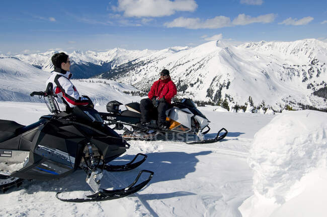 Amigos parar e olhar para a vista enquanto snowmobiling, Monashee montanhas, Valemount, Thompson Okanagan, Colúmbia Britânica, Canadá — Fotografia de Stock