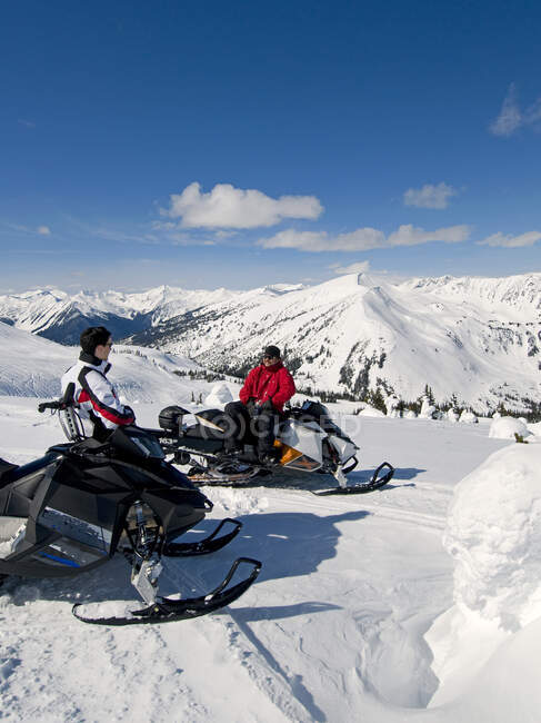 Des amis s'arrêtent et regardent la vue en motoneige, Monashee mountains, Valemount, Thompson Okanagan, Colombie-Britannique, Canada — Photo de stock