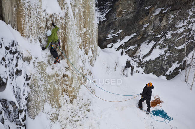 Escaladora observando al hombre escalando hielo fuera de Sherbrooke, Quebec, Canadá - foto de stock