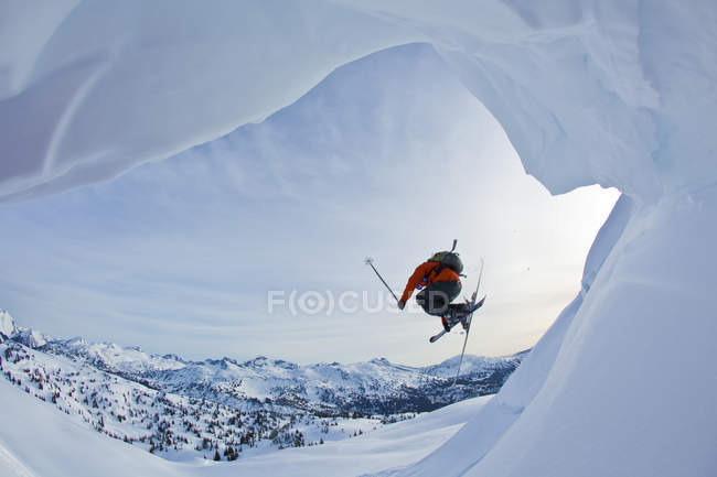Jovem do sexo masculino mais livre pulando cornija enquanto esqui sertanejo em Monashees montanhas, Colúmbia Britânica, Canadá — Fotografia de Stock