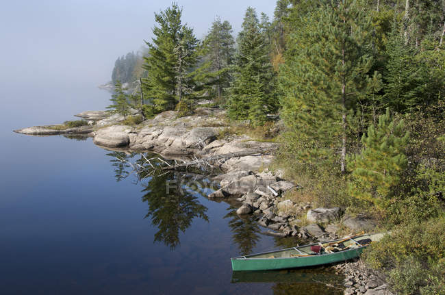 Rocky shoreline of French Lake with beached canoe in Quetico Provincial Park, Canada. — Stock Photo