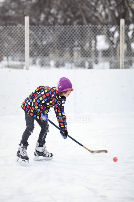 Garçon jouant au hockey sur glace sur la patinoire extérieure — Photo de stock