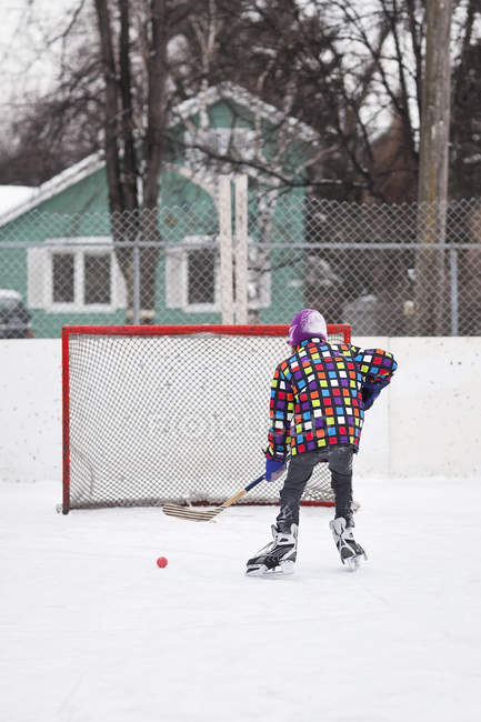 Boy playing ice hockey on outdoor rink — Stock Photo