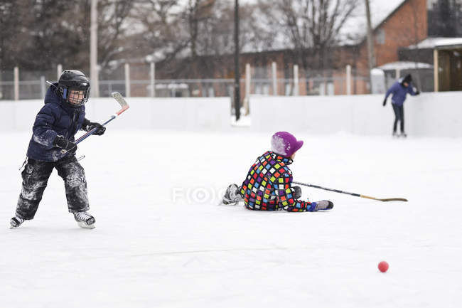 Boys playing ice hockey on outdoor rink — Stock Photo
