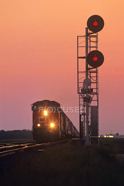 Señales ferroviarias con el tren acercándose en segundo plano cerca de Winnipeg, Manitoba, Canadá - foto de stock