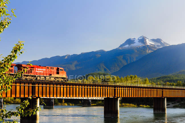 Canadian locomotive crossing rail bridge over Columbia River in Revelstoke, Canadá — Fotografia de Stock