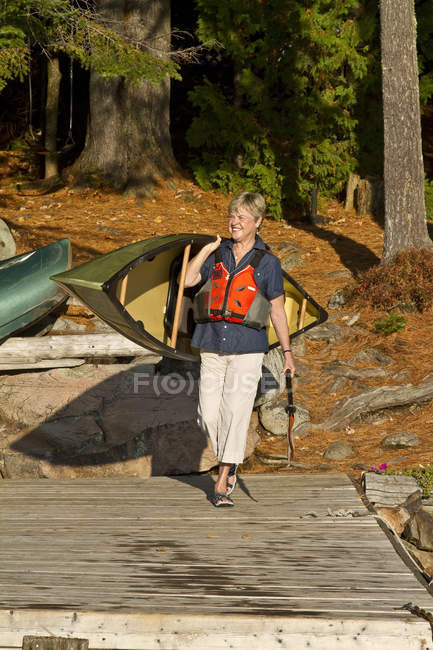 Зрелая женщина, несущая каноэ на озеро Source Lake, Алгонкин Парк, Онтарио, Канада . — стоковое фото