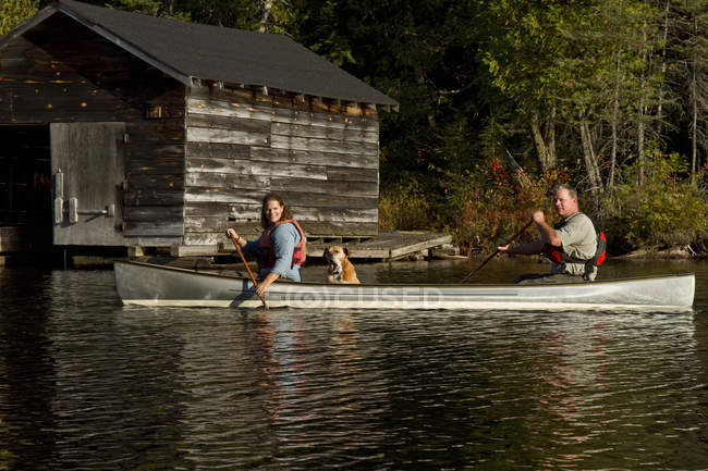 Coppia canoa con cane sul lago sorgente, Algonquin Park, Ontario, Canada . — Foto stock