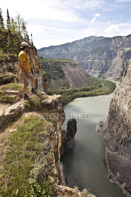 Hombre en la cara del acantilado sobre el río Nahanni cerca de la formación de rocas 