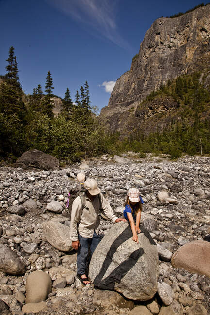 Father and daughter examine interesting rock while hiking up Lafferty Creek on Nahanni River, Nahanni National Park Preserve, NWT, Canada. — Stock Photo