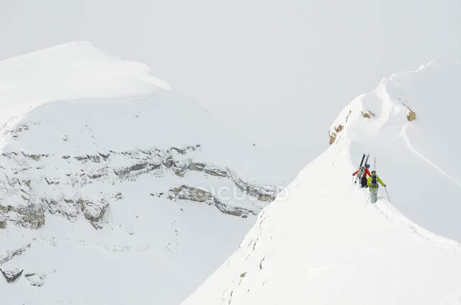 Deux skieurs de l'arrière-pays montent une crête dans l'aire de chute de glace des Rocheuses canadiennes au nord de Golden, en Colombie-Britannique — Photo de stock