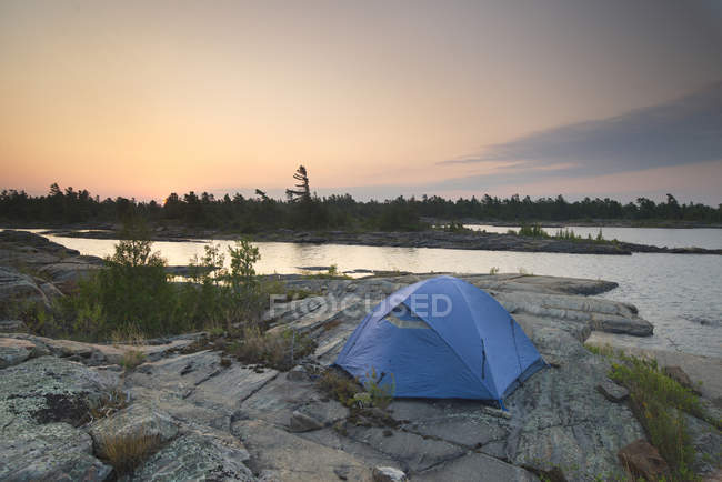 Tienda azul que acampa en la orilla rocosa en la bahía georgiana cerca de Britt, Ontario, Canadá - foto de stock