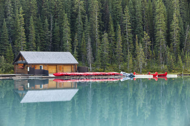 Boathouse e canoas reflexão na água do Lago Louise, Banff National Park, Alberta, Canadá — Fotografia de Stock