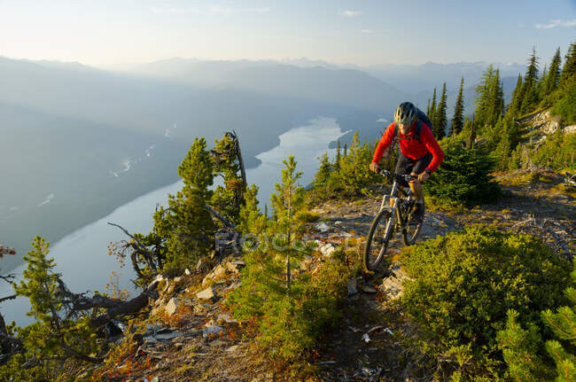 Um ciclista de montanha cavalga alto acima do Lago Kootenay nas Montanhas Purcell da Colúmbia Britânica — Fotografia de Stock