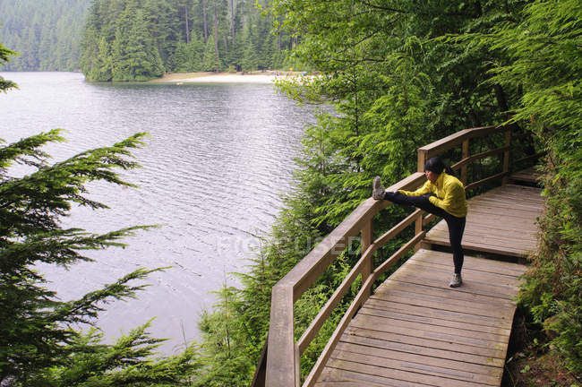 Female runner stretching on boardwalk by Sasamat Lake, Belcarra Regional Park, Port Moody, British Columbia, Canada — Stock Photo