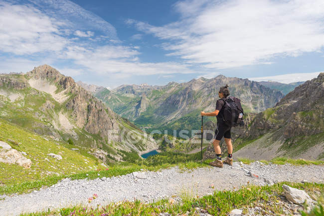 Backpacker caminhadas no caminho e olhando para a visão expansiva a partir do topo. Aventuras de verão e exploração nos Alpes franceses italianos . — Fotografia de Stock