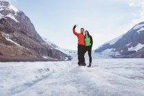 Couple prenant selfie avec téléphone portable près de la montagne — Photo de stock