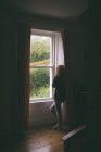 Думлива жінка дивиться у вікно вдома. — стокове фото