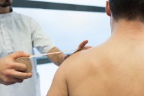 Fisioterapista che applica bende sulle spalle dei pazienti in clinica — Foto stock