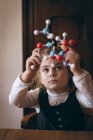 Fille regardant à travers le modèle de molécule à la maison — Photo de stock