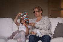 Grand-mère et petite-fille jouent avec le modèle de molécule dans le salon à la maison — Photo de stock