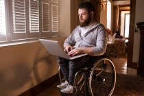 Jeune homme handicapé utilisant un ordinateur portable à la maison — Photo de stock
