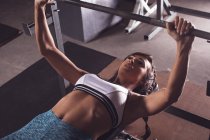 Fit woman lifting the barbell rod in the gym — Stock Photo