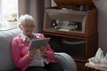 Старшая женщина, использующая цифровой планшет дома — стоковое фото
