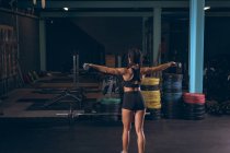 Visão traseira da mulher apta a se exercitar com halteres no ginásio — Fotografia de Stock